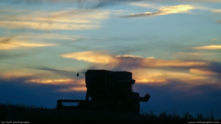 Evening Harvest -- The silhouette of a combine against the sunset